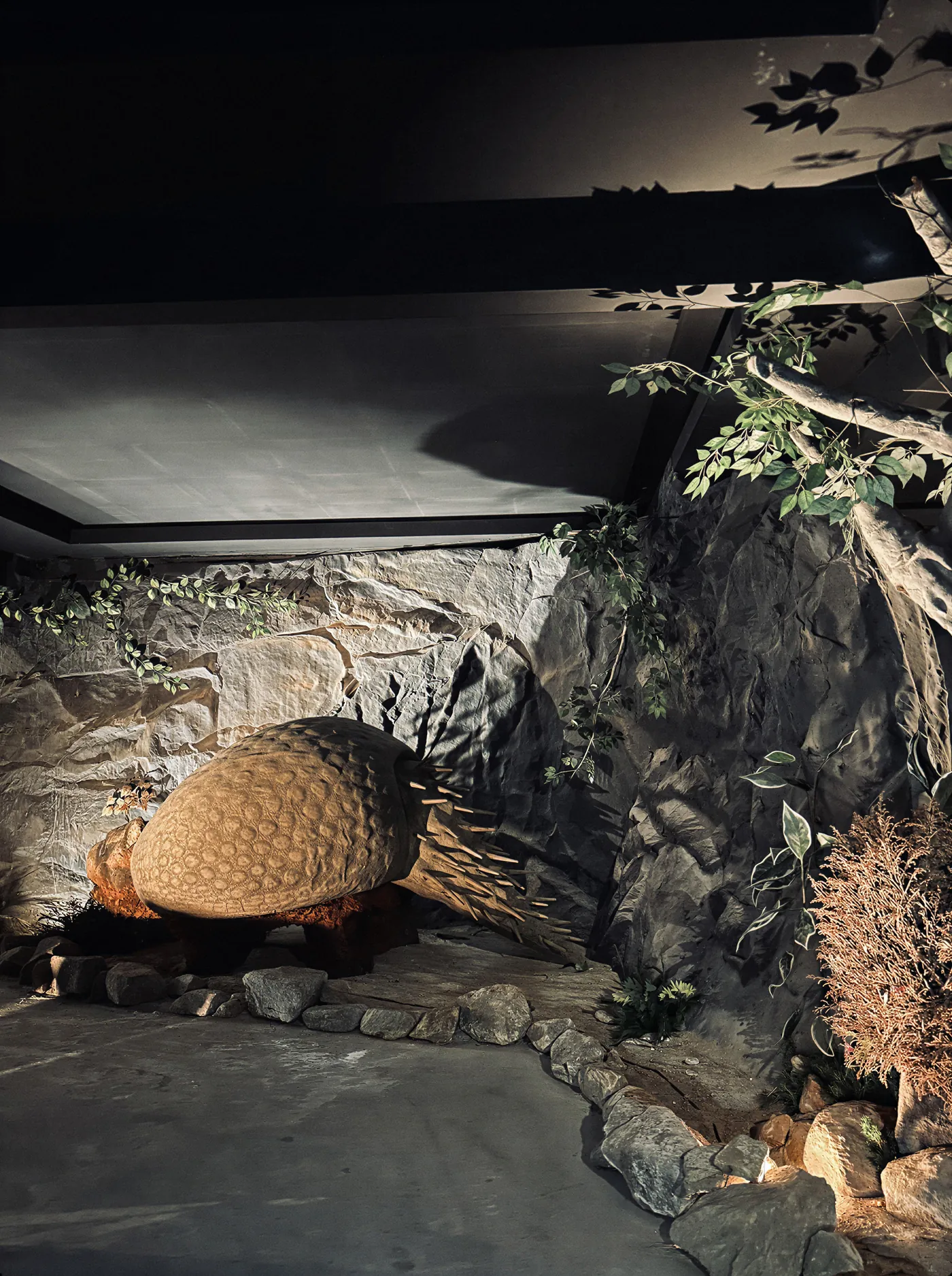 Reconstrução de um gliptodonte com a carapaça de placas ósseas diante de uma parede de pedra.